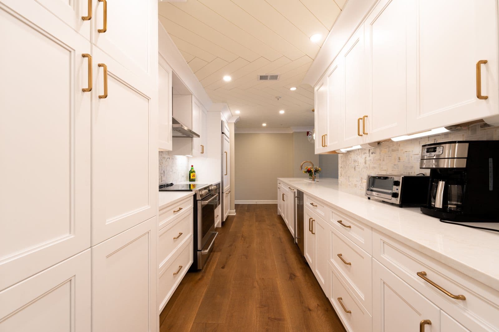 Bright renovated kitchen with white cabinetry, brass hardware, and hardwood flooring