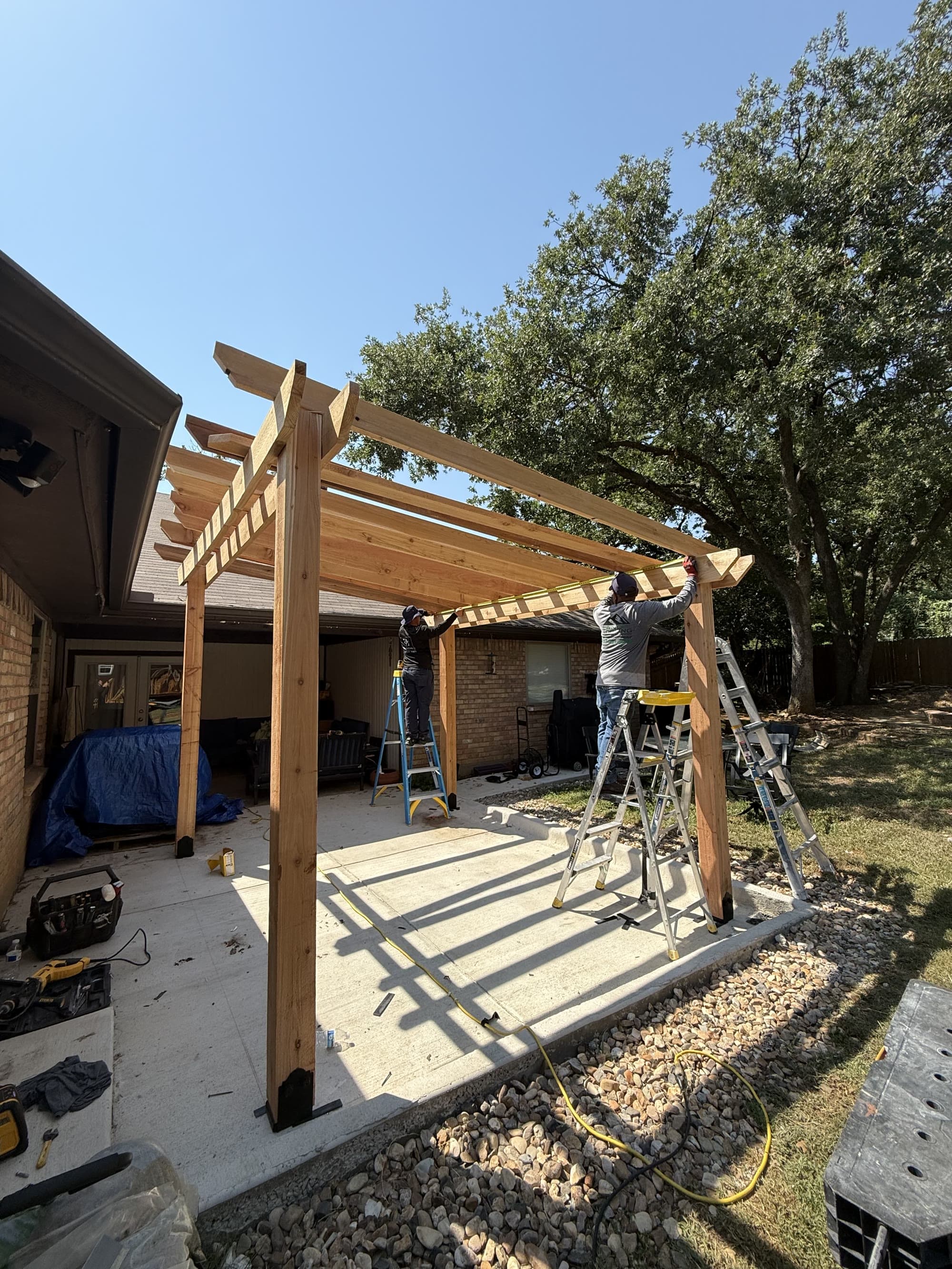 My Dream Home Remodeling crew members building a cedar pergola on a backyard patio