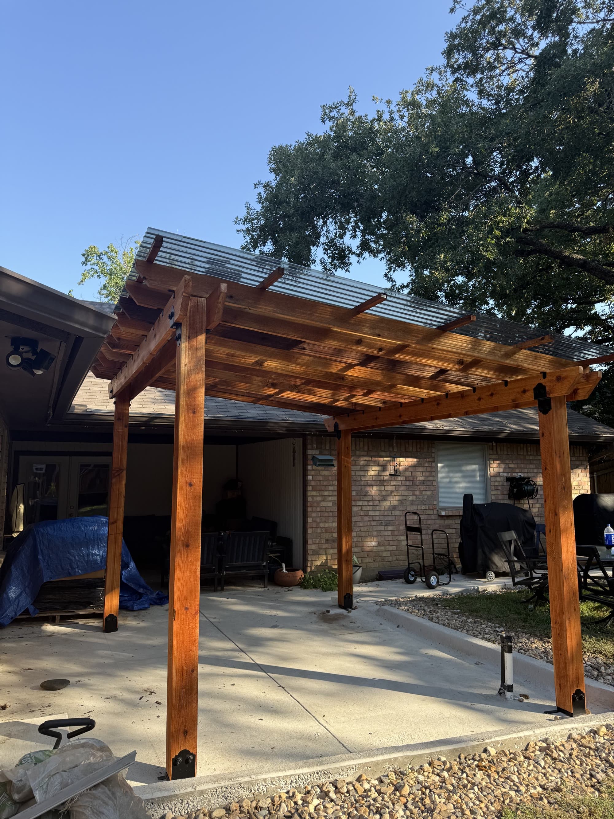 Completed cedar pergola with a corrugated roof over a backyard patio