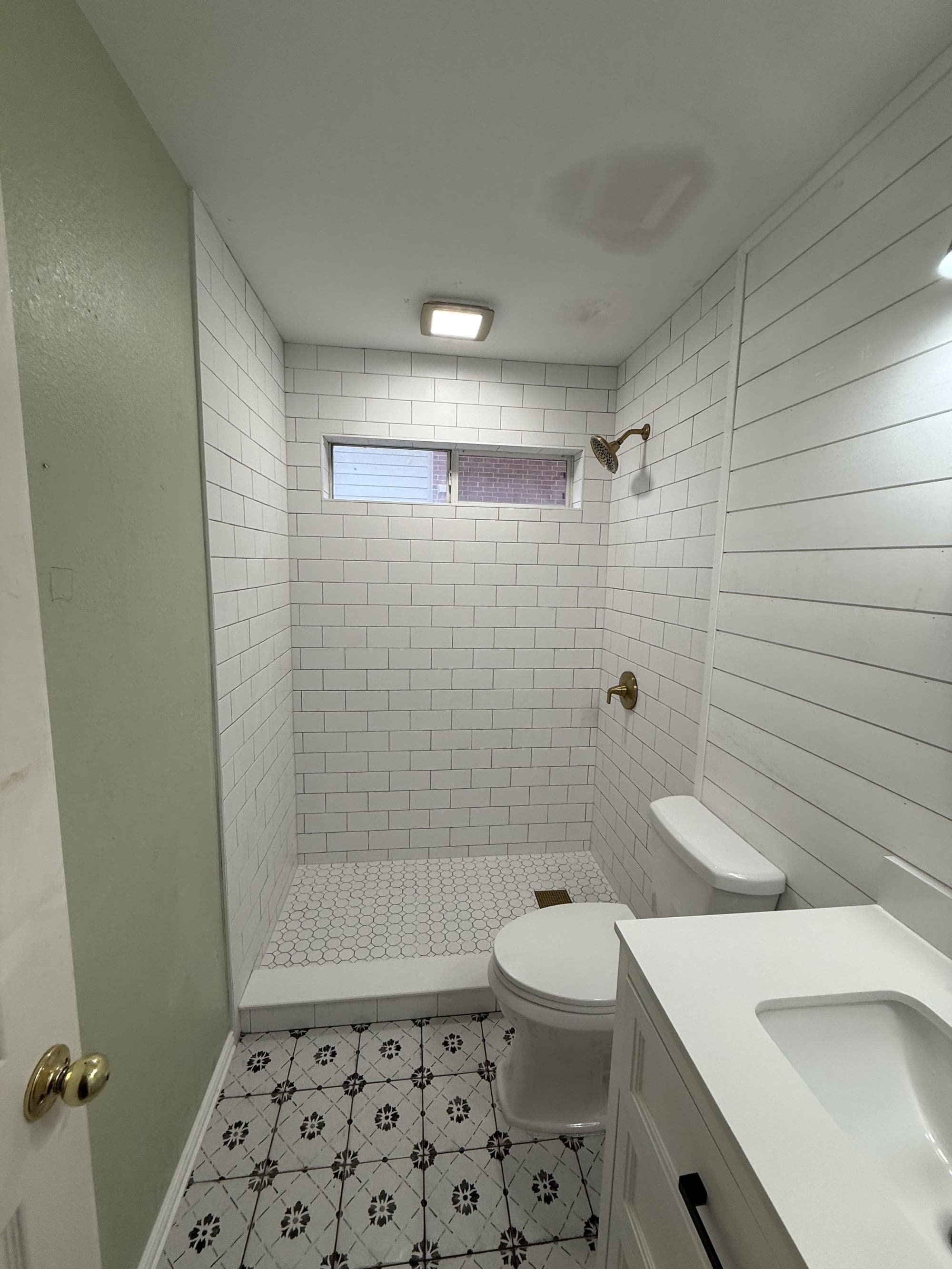 Finished walk-in shower with white subway tile, shiplap accent wall, and patterned floor tile