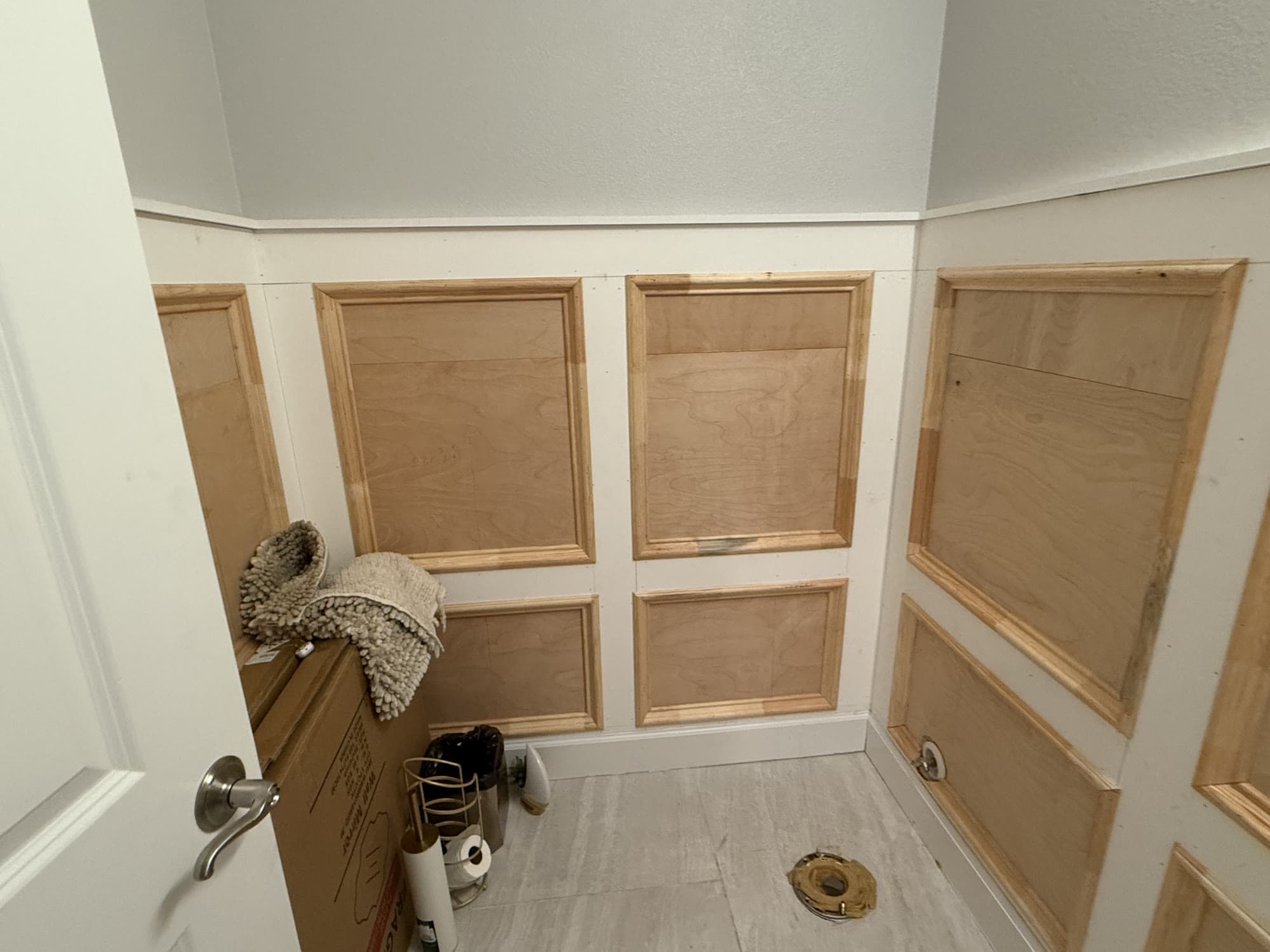 Bathroom wall wainscoting installation in progress with raw wood panels