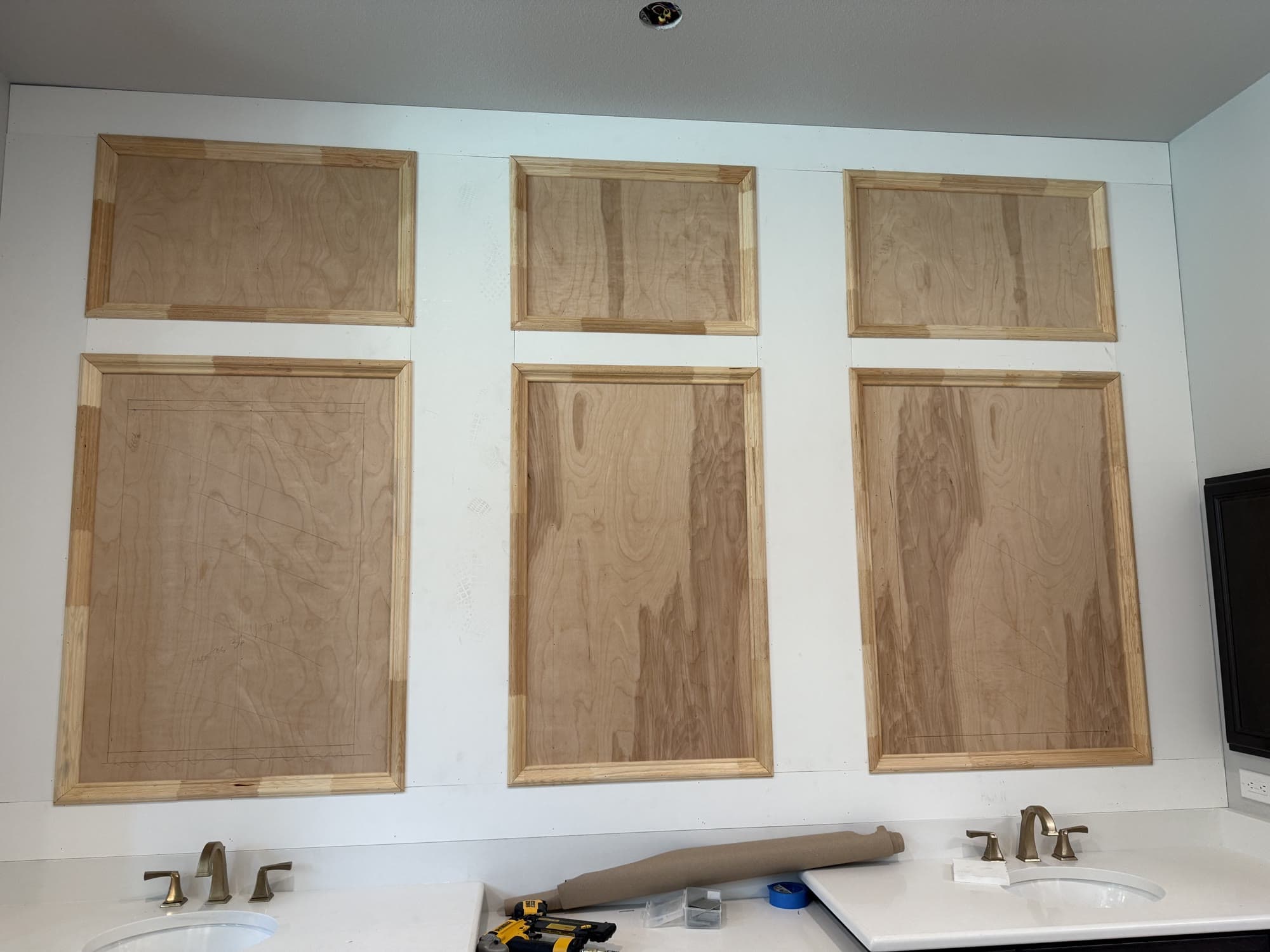 Raw wood wainscoting panels being installed above a double bathroom vanity