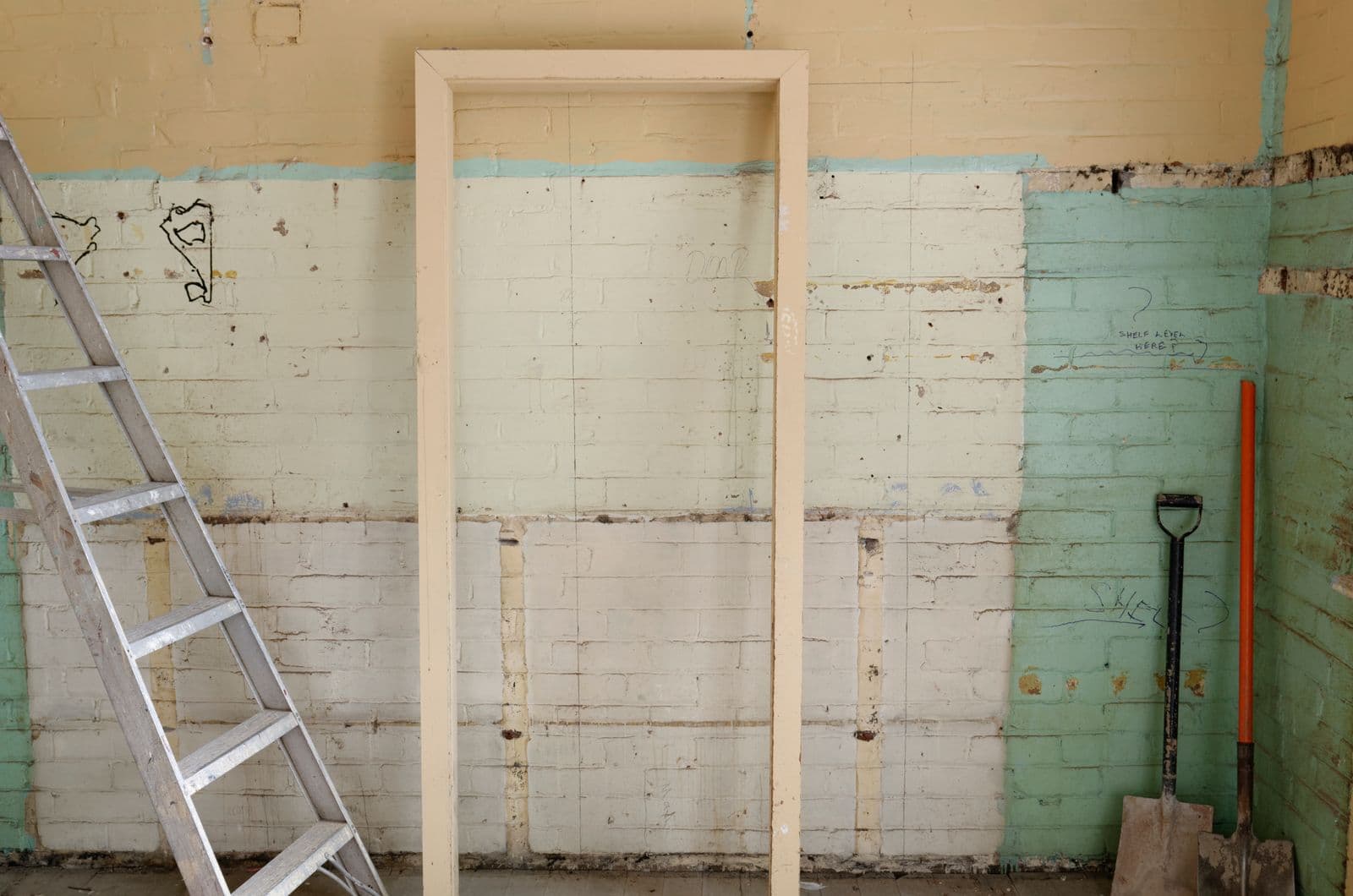 Interior room mid-renovation with a ladder, framing, and demolition tools