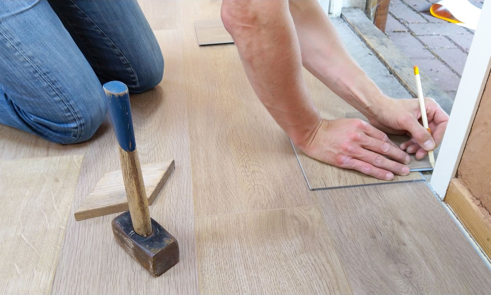 Flooring installer measuring and marking wood floor panels before cutting