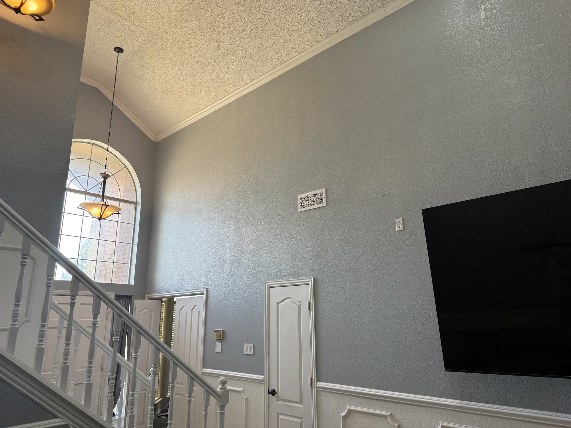 Two-story great room with freshly painted blue-gray walls and a mounted TV
