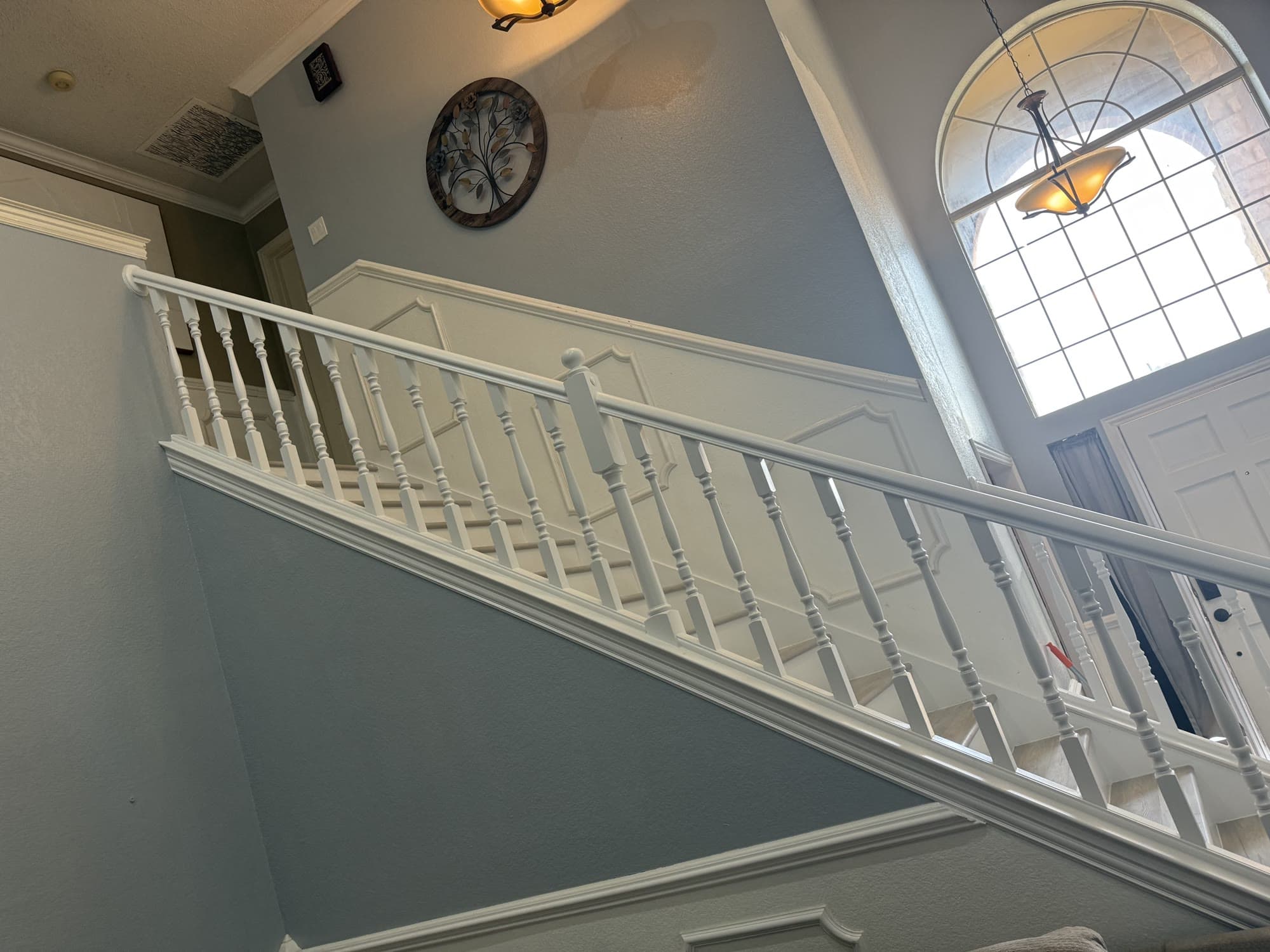 Freshly painted blue-gray two-story staircase wall with white trim