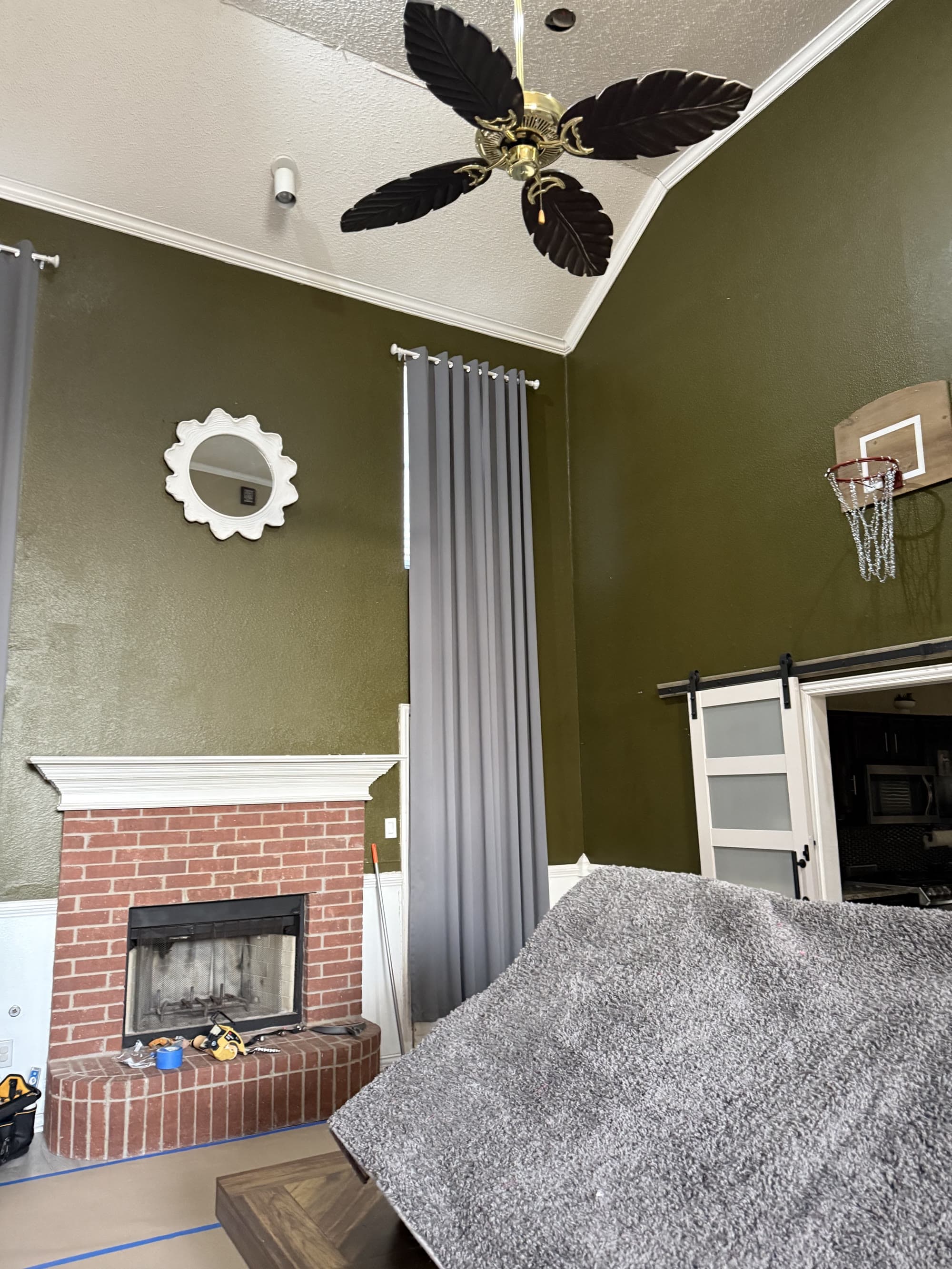 Living room with freshly painted olive green walls and a brick fireplace