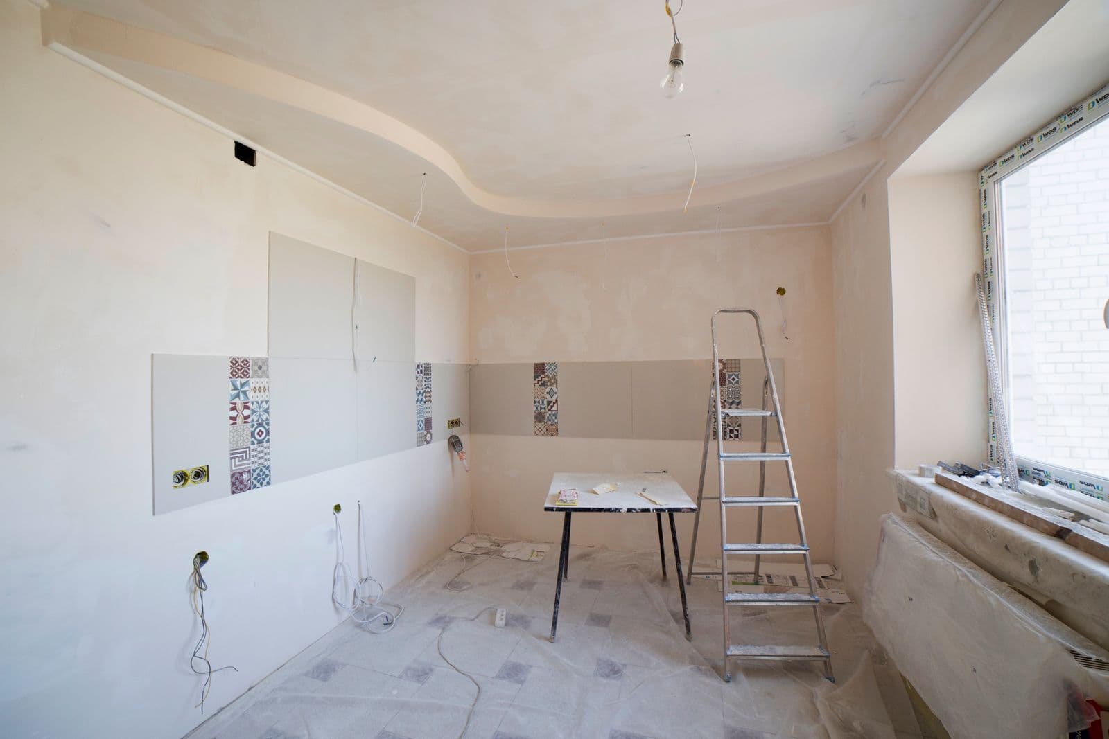 Spacious kitchen mid-renovation with a ladder and tools set up during cabinet work