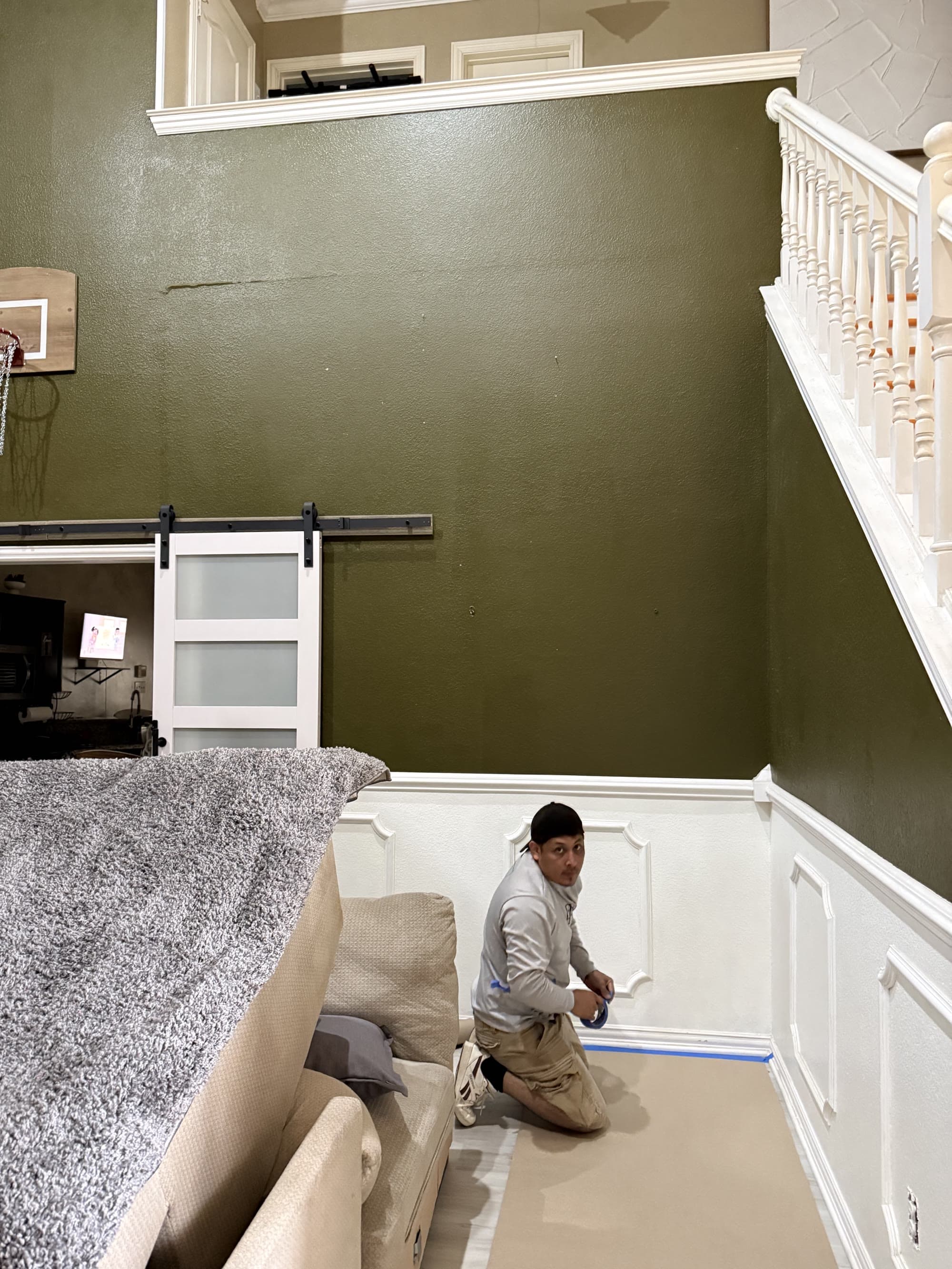 My Dream Home Remodeling crew member taping off wainscoting before painting a staircase wall